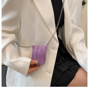 Detail view of mini purple woven metal chain bag worn over a white stylish blazer