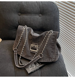 Close-up of charcoal denim tote bag with silver chain strap and large metal buckle