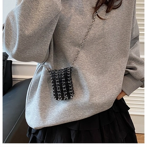 Detail of mini black chain-mail crossbody bag with silver chain strap on model
