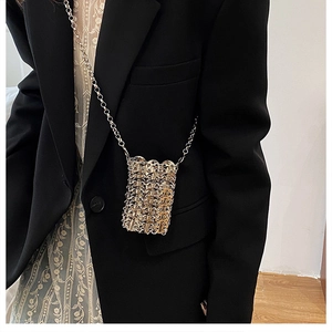 Detail of handmade gold metal sequin chain link woven crossbody bag on a black blazer