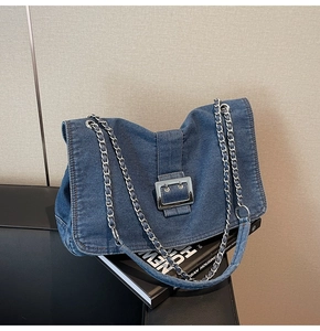 Detail of blue denim tote bag with silver metal chain strap and square buckle closure