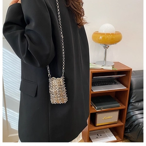 Close-up of silver metal mesh mini bag with chain strap on a black blazer