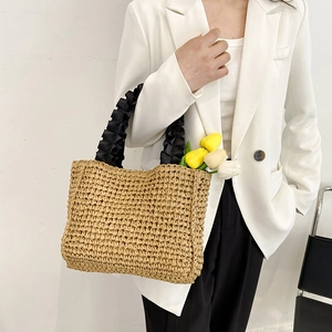 Handmade woven straw handbag with black pleated fabric handles for beach vacation style