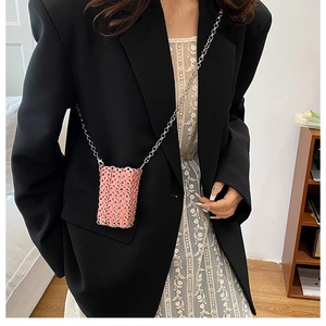 Detail of pink woven mini bag with silver metal rings and chic chain strap