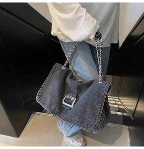 Detail view of washed denim tote with large silver buckle and chain shoulder strap