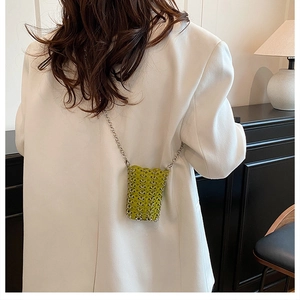 Lime green woven mini crossbody bag shown on a white blazer with a silver chain