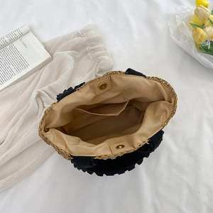 Straw woven tote bag with black ruffle handles showing internal pocket and magnetic closure