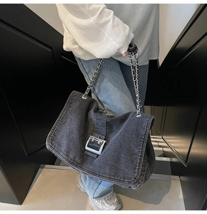 Close-up of black denim tote bag with large silver square buckle and chain strap