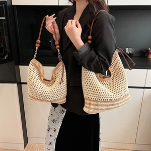 Set of two hollow woven straw tote bags with brown leather handles and wooden bead accents
