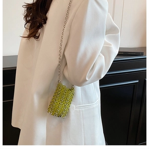 Detail view of mini neon green hollow mesh bag with silver chain on white blazer