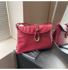 Close-up of burgundy leather bag with woven cord trim and gold buckle detail