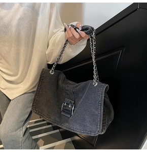 Detail of black washed denim shoulder bag with silver buckle and metal chain strap
