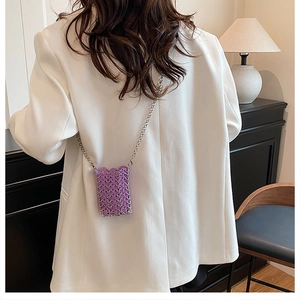 Detailed view of purple hand-woven sequin mini bag with silver metal chain on white blazer