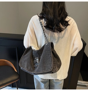 Detail of dark grey denim tote with large vintage metal buckle and chain strap