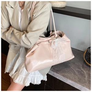 Detail of light pink faux leather tote bag with elegant white lace bow and pearl charm