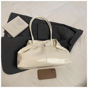 Close-up of cream white faux leather tote bag with soft pleated texture and shoulder strap