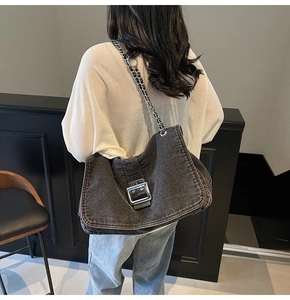 Detail of grey denim hobo bag featuring large silver buckle and chain shoulder strap