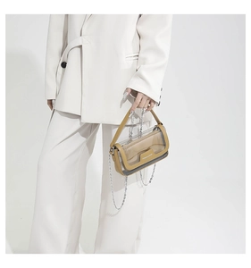 Dettaglio della borsa in PVC trasparente con finiture in pelle marrone e catena