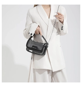 Sac bandoulière transparent en PVC avec chaîne en métal porté sur un blazer blanc