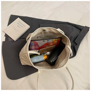 Top-down view of a white large-capacity tote bag showing organized daily essentials