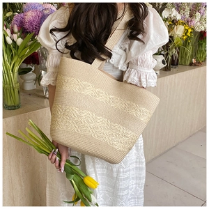 Detail of cream straw tote bag featuring wavy woven texture worn with a white lace dress