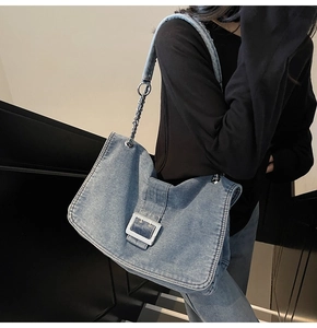 Detail of blue denim tote bag with oversized silver buckle and chain shoulder strap
