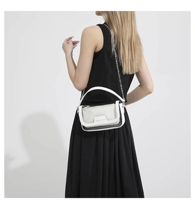 Detail der weißen PVC-Gelee-Tasche mit Metallkette, getragen von einem Modell in Schwarz