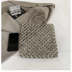 Détail d'un sac cabas argenté en perles sur tissu blanc avec un style moderne minimaliste