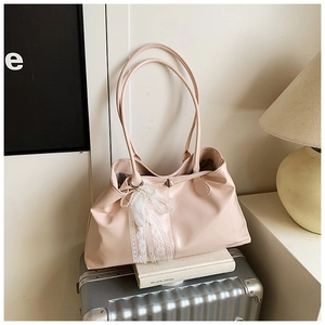 Detail of pink tote bag with lace bow and pearl pendant on a silver suitcase