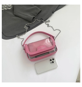 Dettaglio della borsa a tracolla rosa in PVC con catena e manico accanto a un telefono