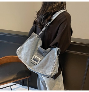 Detail of light blue washed denim tote bag featuring large silver square metal buckle