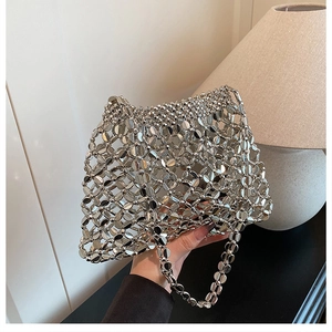 Detail van zilveren pailletten handtas met holle roosterstructuur en metalen ringverbindingen