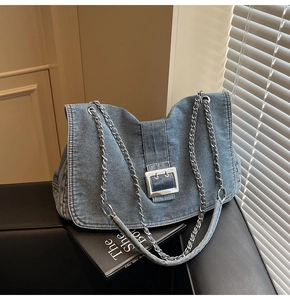 Detail of vintage blue denim tote with silver buckle and chain strap on leather chair