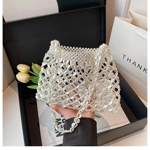 Detailopname van een witte parelhandtas met elegant hol maasontwerp en kralen
