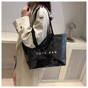 Detail of glossy black waterproof tote bag with bold white text on wide woven strap