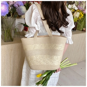 Detailed texture of hand-woven beige straw tote bag with braided patterns and large handle
