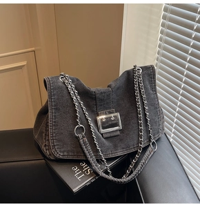 Macro detail of dark grey denim tote with chunky silver chain and metal buckle