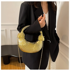 Detail of golden crescent handbag with wave texture on a black suit shoulder