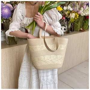 Close-up of handmade woven straw tote bag with wave texture in a floral garden setting