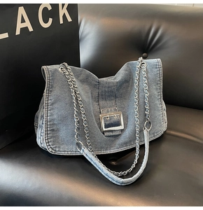 Detail view of denim tote bag with silver metal buckle and chain shoulder strap