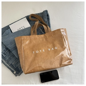 Detail view of brown tote bag with PVC coated texture and white TOTE BAG lettering