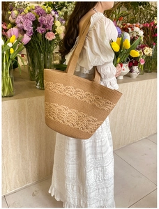 Detailed wave pattern weaving on a large khaki straw beach tote bag worn by a model