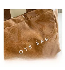 Detail of Tyvek paper material under transparent PVC layer on brown tote bag