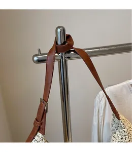 Detail of adjustable dark brown leather strap and silver buckle on a woven straw bag