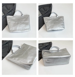 Macro detail of silver tote bag showing metallic texture and white TOTE BAG lettering