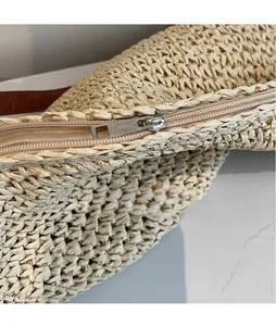 Detail of silver metal zipper and tight woven texture on the beige straw shoulder bag