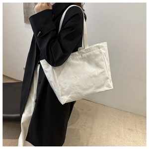Detailed view of white tote bag with textured crinkle finish and TOTE BAG embossing