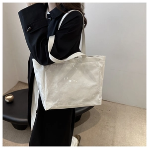 Detail of white wrinkled DuPont paper tote bag with TOTE BAG embossing and woven handle