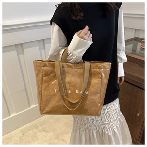 Close-up of brown textured tote bag with white TOTE BAG lettering and woven straps