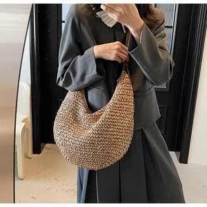 Detail of hand-woven straw hobo bag featuring premium brown leather shoulder strap